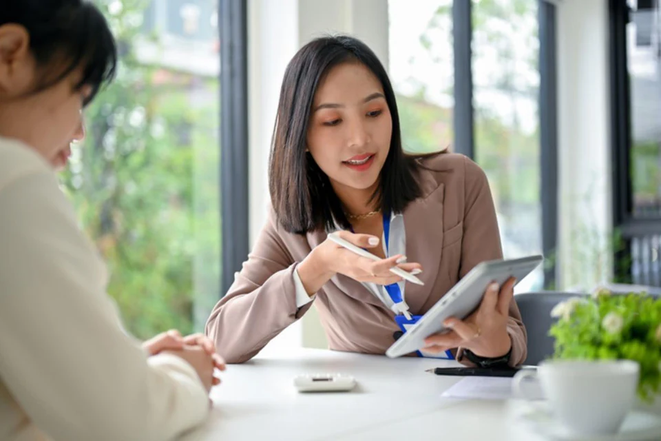 Finance adviser guiding a customer through an application on a tablet.