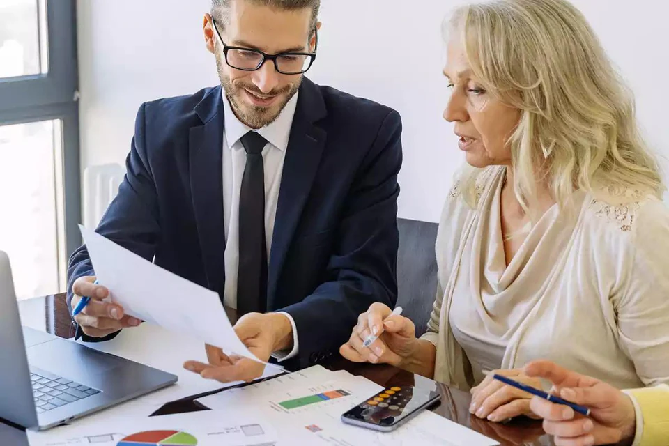Finance adviser reviewing calculations and reports with a client.